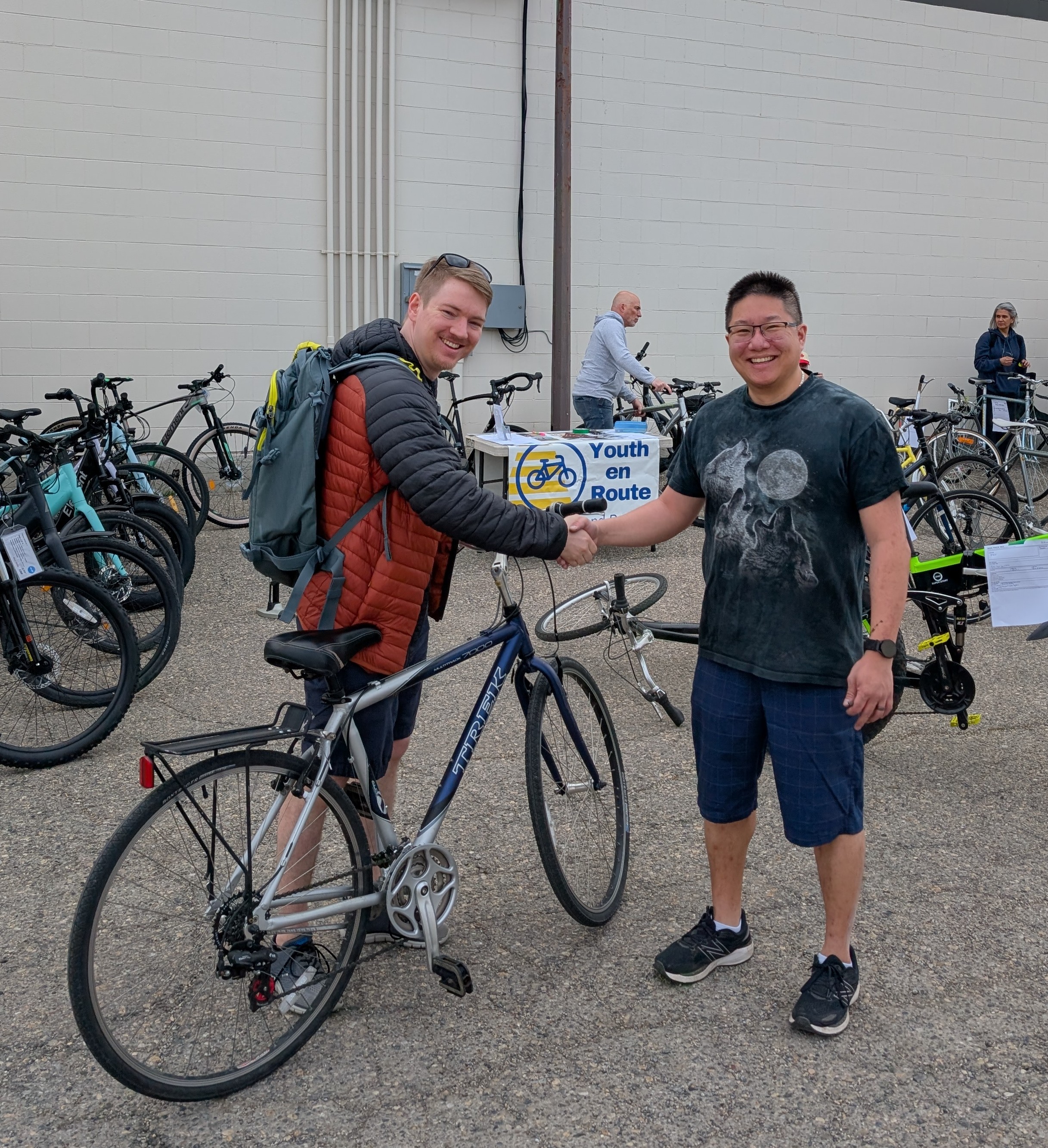 Two people shaking hands after a bike sale at YYC Bike Swap